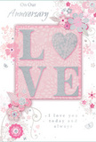 This anniversary card offers a gentle yet deeply felt celebration of enduring romance, its soft pastel pinks and refined silvery greys capturing the mood of a quiet moment tucked away from Soho's lively streets. At the centre, the word LOVE is formed in raised glitter lettering, each stroke soft and rounded, creating a tactile highlight that draws both eye and hand. The letter O is lovingly replaced by a shimmering silver heart, its textured surface reflecting light with a subtle metallic sheen, like streetlights glancing off rain-dampened cobbles near Old Compton Street. Surrounding this focal point, a halo of delicate blooms unfurls, their petals painted in blush and mauve tones with an almost watercolour softness. The outlines are fine and flowing, giving an impression of movement, as if the flowers were just arranged by a florist and are still settling into place. Scattered among the blossoms are tiny decorative flourishes - swirling lines, small petals, and light, almost elusive butterflies that introduce a hint of whimsy. The pale pink background remains calm and uncluttered, allowing the florals and silver details to shimmer gently rather than compete for attention. Across the design, elegant script spells out On Our Anniversary and I love you today and always, the lettering slender and graceful, as though carefully written by hand in a quiet bar on Greek Street after an evening of reflection. The overall feel is intimate and sincere, like a treasured keepsake you'd tuck inside a favourite book, paired with a fresh anniversary bouquet delivered across Soho and the neighbouring West End - a lasting reminder of shared journeys and the soft, steady glow of committed love.